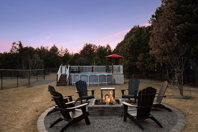 patio terrace at dusk with a fenced in pool, fence, and an outdoor fire pit