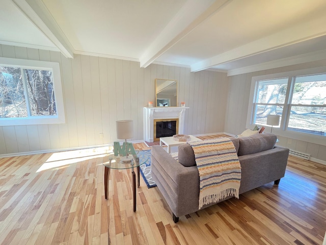 living area featuring a glass covered fireplace, beamed ceiling, wood finished floors, and visible vents