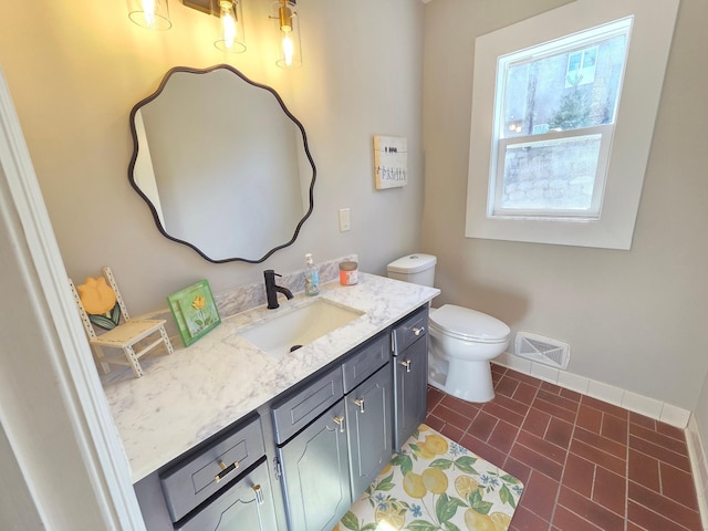 bathroom with toilet, visible vents, vanity, and baseboards