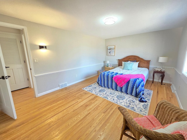 bedroom with baseboards, visible vents, and light wood finished floors