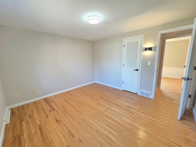 spare room featuring visible vents, light wood-style flooring, and baseboards