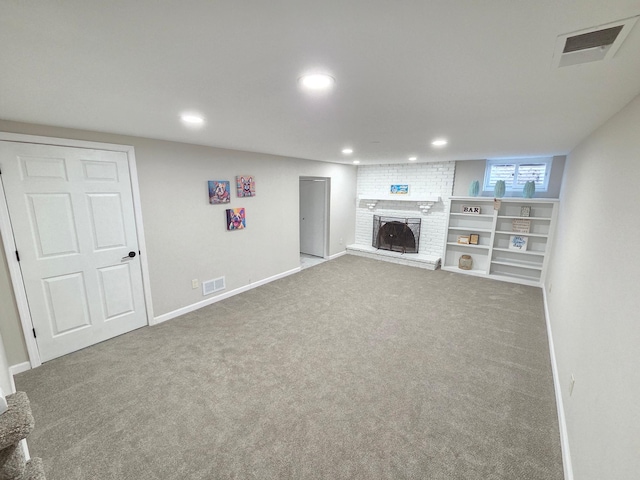 below grade area featuring carpet, a brick fireplace, visible vents, and recessed lighting