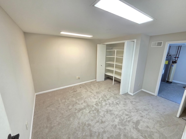 unfurnished bedroom featuring visible vents, baseboards, water heater, a closet, and carpet