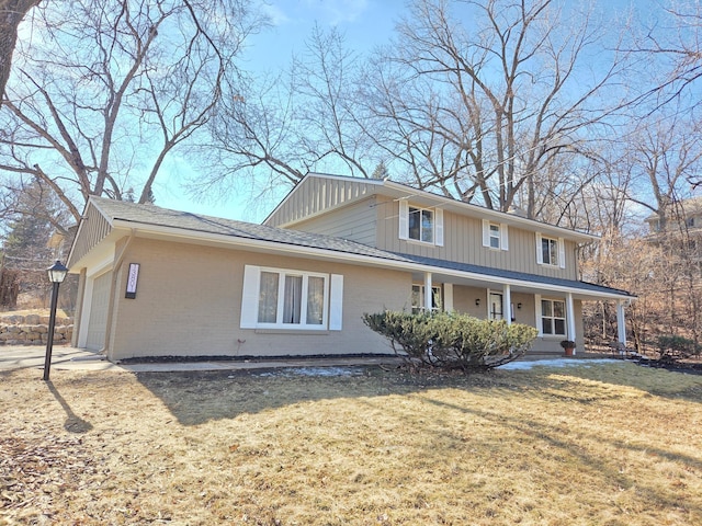 view of front of home with brick siding, a porch, an attached garage, and a front yard