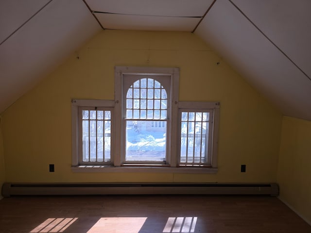 additional living space featuring a baseboard heating unit, lofted ceiling, and wood finished floors