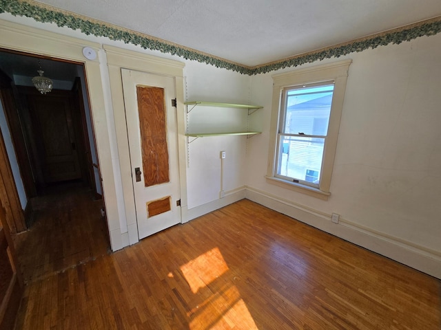 spare room with a notable chandelier and wood finished floors