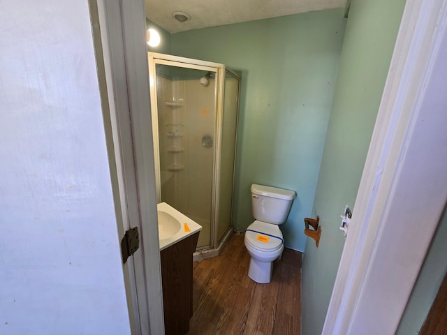 full bathroom with a stall shower, vanity, toilet, and wood finished floors