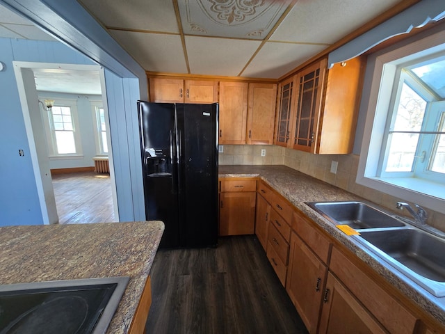 kitchen featuring black appliances, dark wood-style flooring, dark countertops, and glass insert cabinets