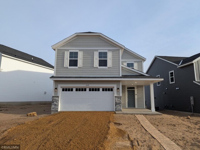 craftsman-style house featuring a garage, stone siding, covered porch, and driveway