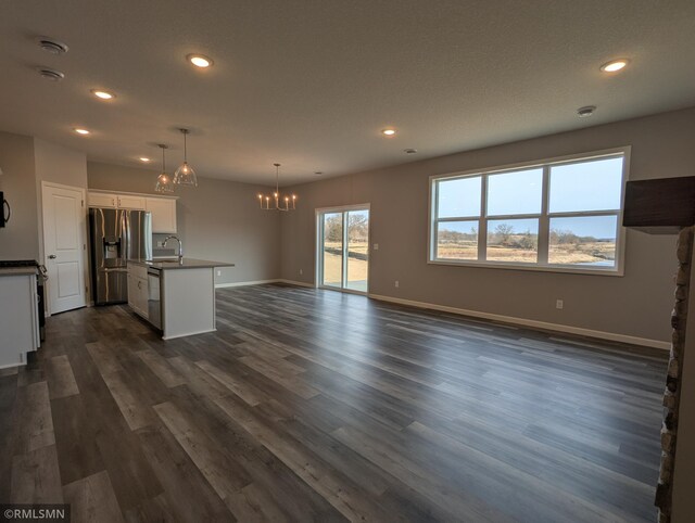 unfurnished living room featuring dark wood-style floors, a notable chandelier, recessed lighting, and baseboards