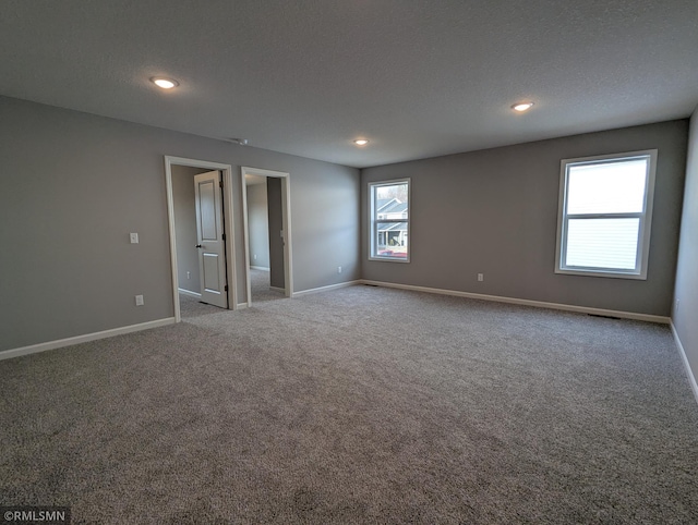 empty room with recessed lighting, carpet, baseboards, and a textured ceiling