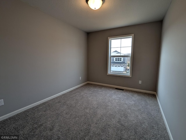 spare room with visible vents, a textured ceiling, carpet, and baseboards