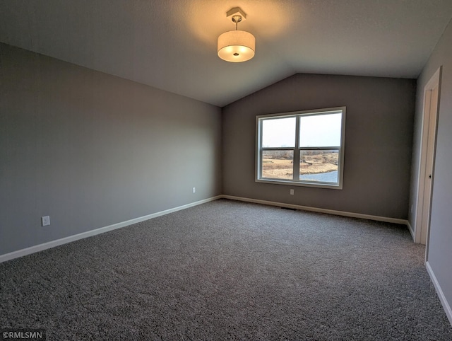 empty room with vaulted ceiling, carpet flooring, and baseboards