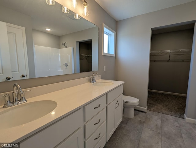 bathroom featuring toilet, walk in shower, baseboards, and a sink