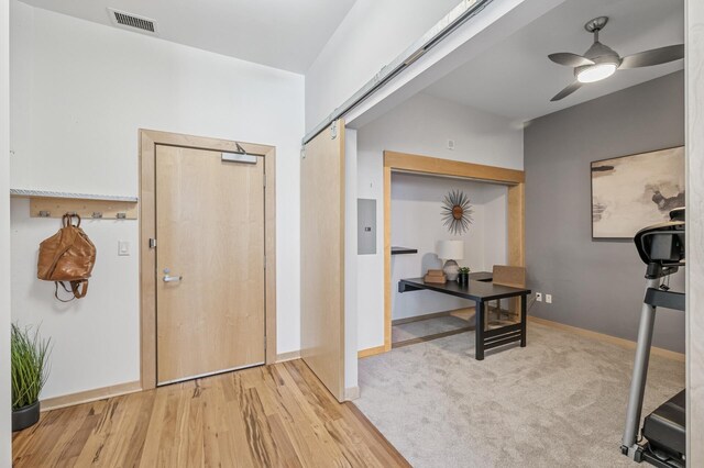 entryway with baseboards, visible vents, ceiling fan, wood finished floors, and carpet