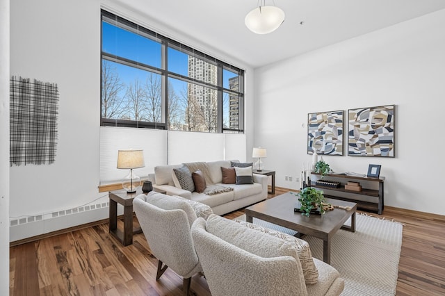 living room with baseboard heating, floor to ceiling windows, baseboards, and wood finished floors