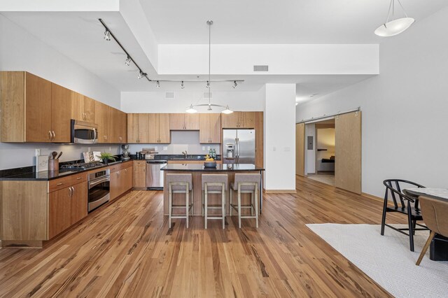 kitchen featuring dark countertops, a barn door, a breakfast bar area, and stainless steel appliances