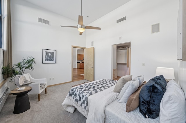 bedroom with a high ceiling, carpet flooring, visible vents, and baseboards