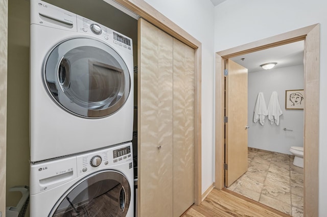 laundry area featuring laundry area, stacked washer / dryer, and light wood-style flooring