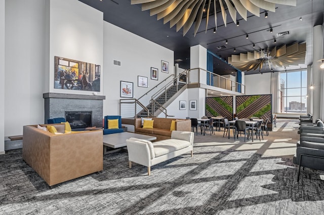 interior space featuring visible vents, a high ceiling, stairway, and a glass covered fireplace