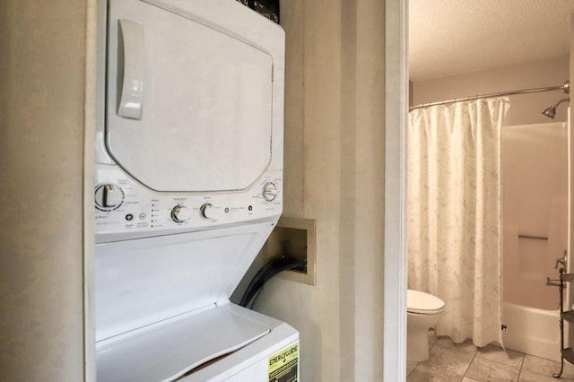 laundry area with a textured ceiling, stacked washer and dryer, and laundry area