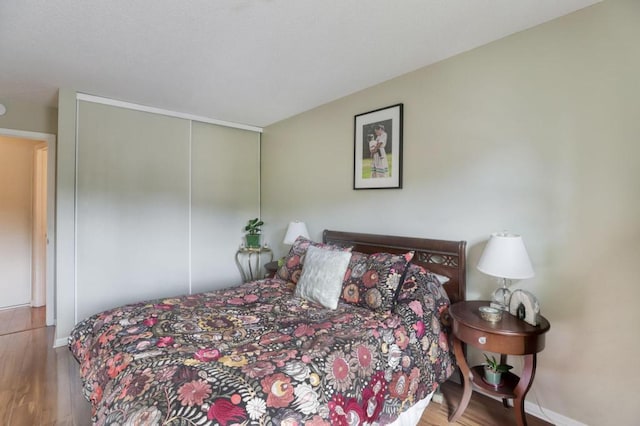 bedroom with a closet, baseboards, and wood finished floors