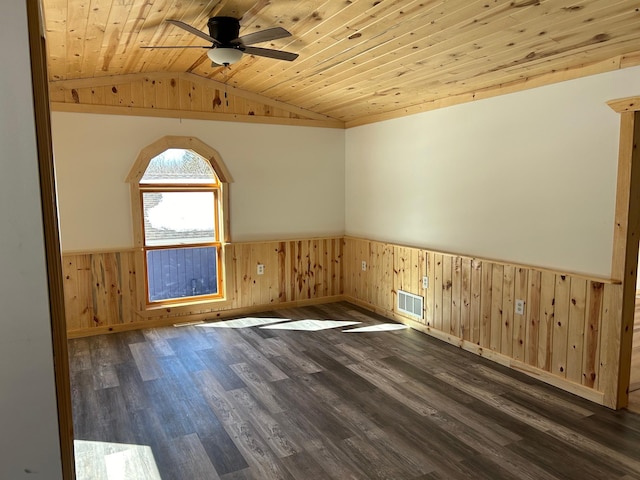 empty room with visible vents, dark wood finished floors, a wainscoted wall, vaulted ceiling, and wooden ceiling