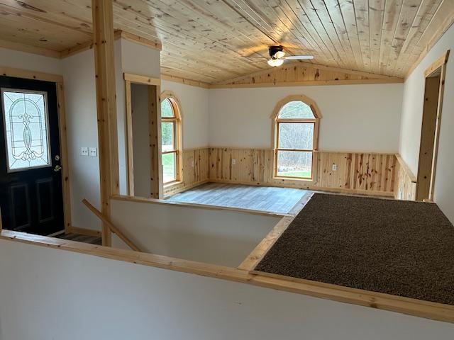 31154 Arbo Rd, Arbo Twp, MN 55744 - unfurnished room featuring lofted ceiling, a ceiling fan, wainscoting, wood ceiling, and wood walls