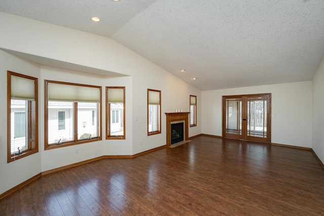 unfurnished living room with lofted ceiling, a fireplace with flush hearth, wood finished floors, and a healthy amount of sunlight