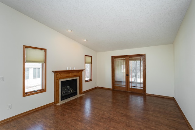 unfurnished living room featuring baseboards, lofted ceiling, wood finished floors, and a tiled fireplace