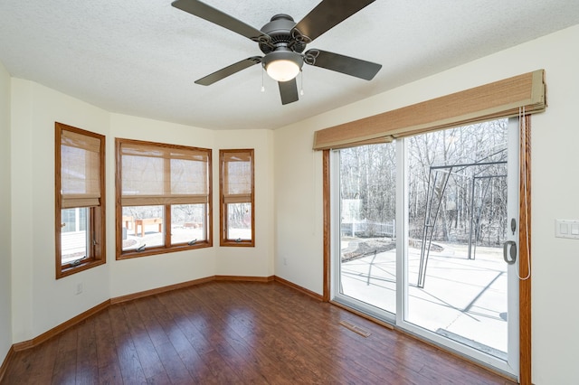 empty room featuring visible vents, baseboards, a textured ceiling, and dark wood finished floors