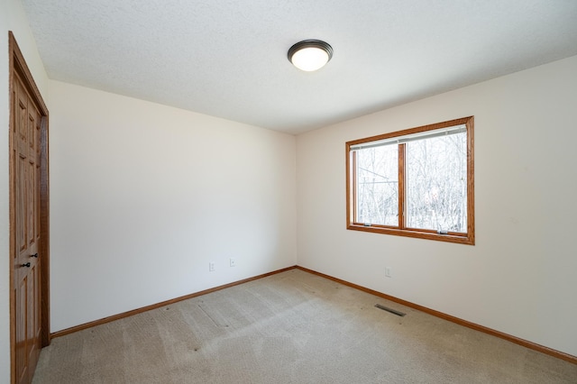 empty room featuring baseboards, visible vents, and light carpet