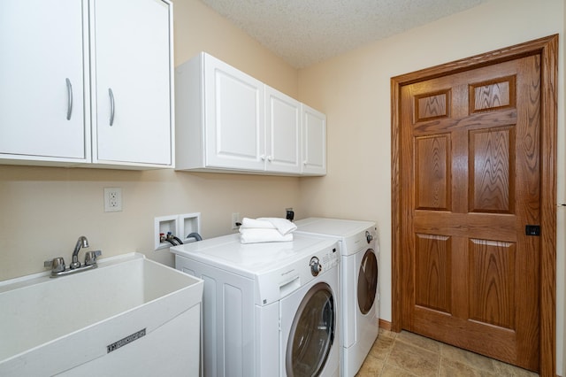 laundry room featuring a sink, a textured ceiling, washing machine and dryer, cabinet space, and light tile patterned floors