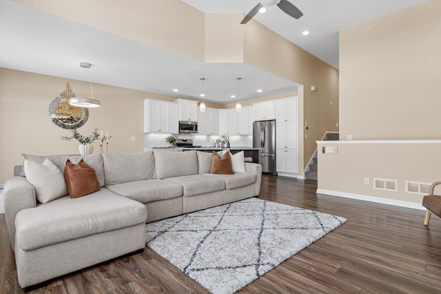 living room featuring recessed lighting, dark wood-style flooring, visible vents, and stairs