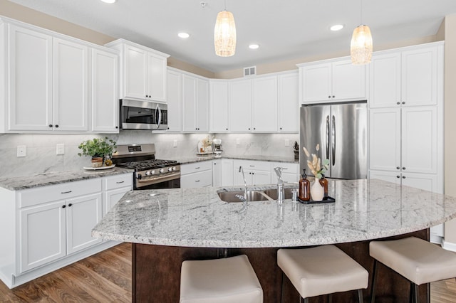 kitchen featuring stainless steel appliances, a breakfast bar area, wood finished floors, and decorative backsplash