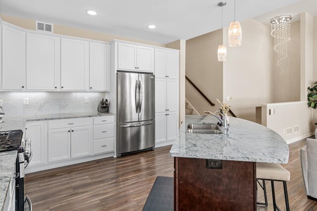 kitchen with appliances with stainless steel finishes, visible vents, a sink, and dark wood-style floors