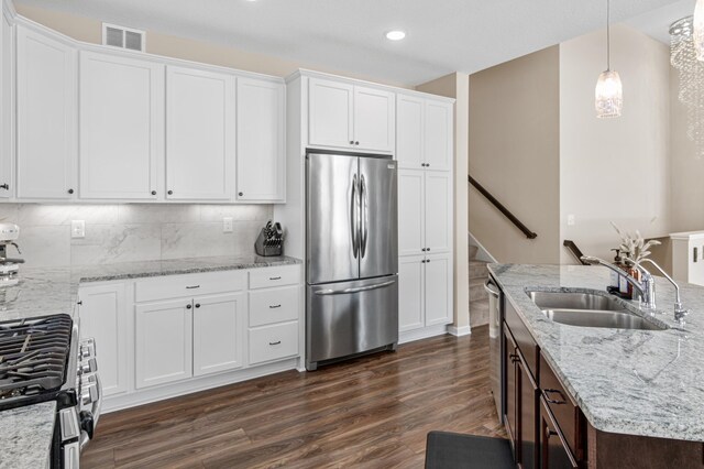 kitchen with appliances with stainless steel finishes, dark wood-style flooring, a sink, and white cabinetry