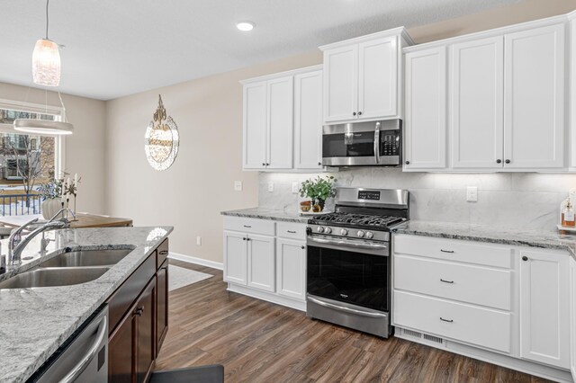 kitchen with stainless steel appliances, a sink, white cabinetry, decorative backsplash, and dark wood finished floors