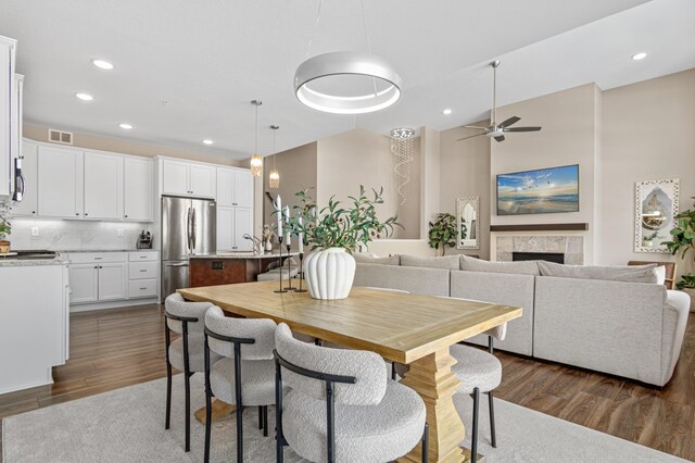 dining area featuring a tile fireplace, visible vents, dark wood-type flooring, and recessed lighting