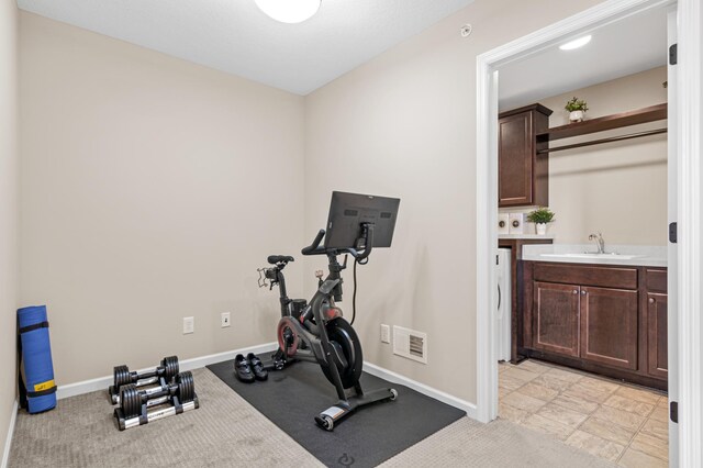 workout room featuring washer / clothes dryer, a sink, visible vents, and baseboards