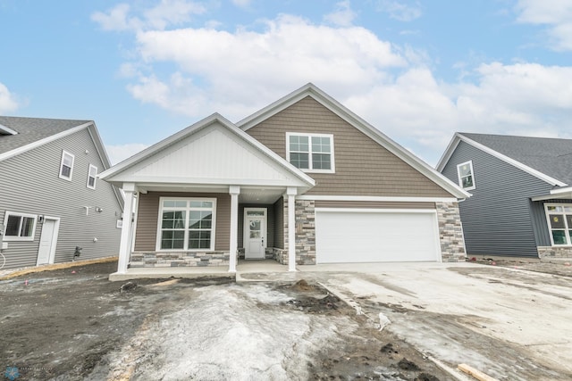 view of front of house with stone siding, covered porch, and a garage