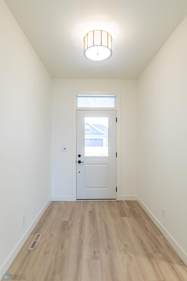 doorway to outside featuring visible vents, baseboards, and light wood finished floors