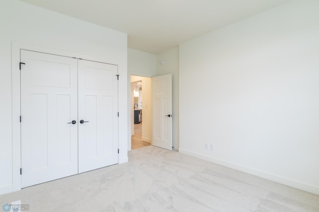 unfurnished bedroom featuring a closet, light colored carpet, and baseboards