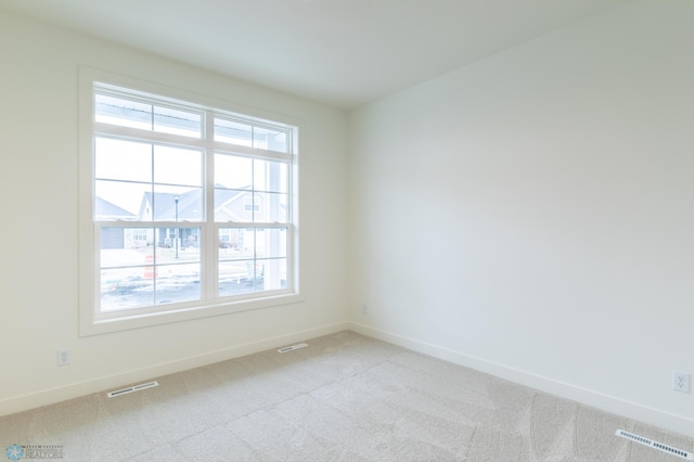 unfurnished room with visible vents, baseboards, and light colored carpet