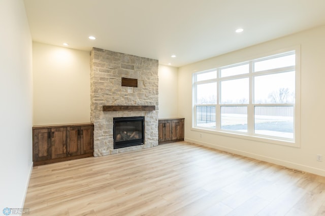 unfurnished living room with visible vents, wood finished floors, recessed lighting, a fireplace, and baseboards