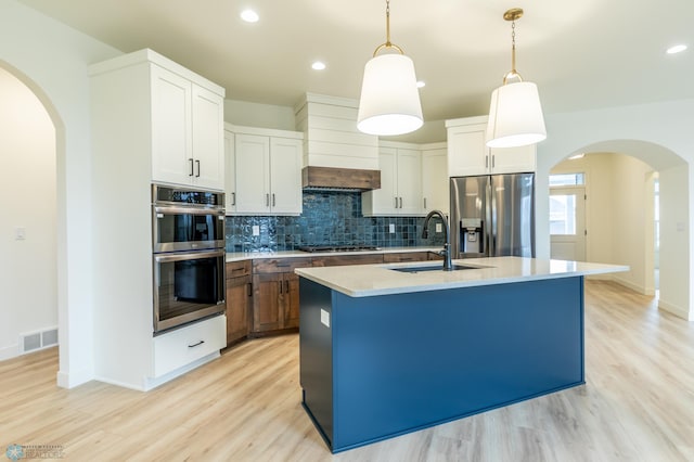 kitchen featuring tasteful backsplash, visible vents, arched walkways, and appliances with stainless steel finishes