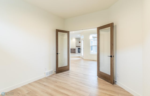 spare room featuring baseboards, french doors, visible vents, and light wood-type flooring