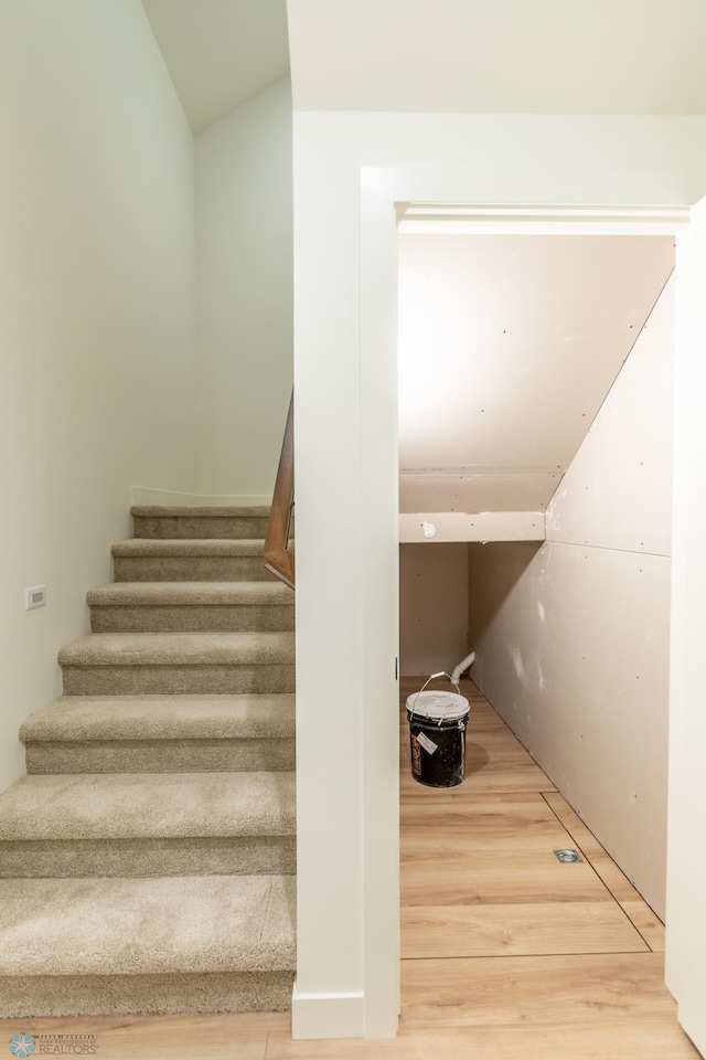 stairway featuring lofted ceiling and wood finished floors