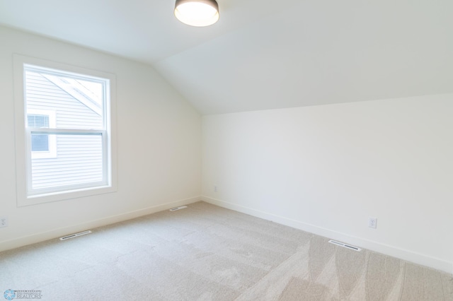 bonus room with visible vents, lofted ceiling, light colored carpet, and baseboards