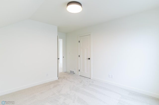 unfurnished room featuring vaulted ceiling, visible vents, baseboards, and light carpet